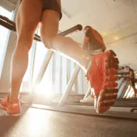 woman with slim toned legs running on treadmill