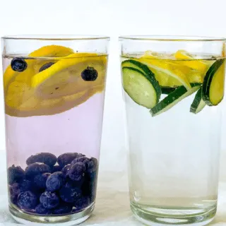 4 glasses of water with fruit infused and fruit floating on top