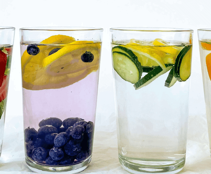 4 glasses of water with fruit infused and fruit floating on top