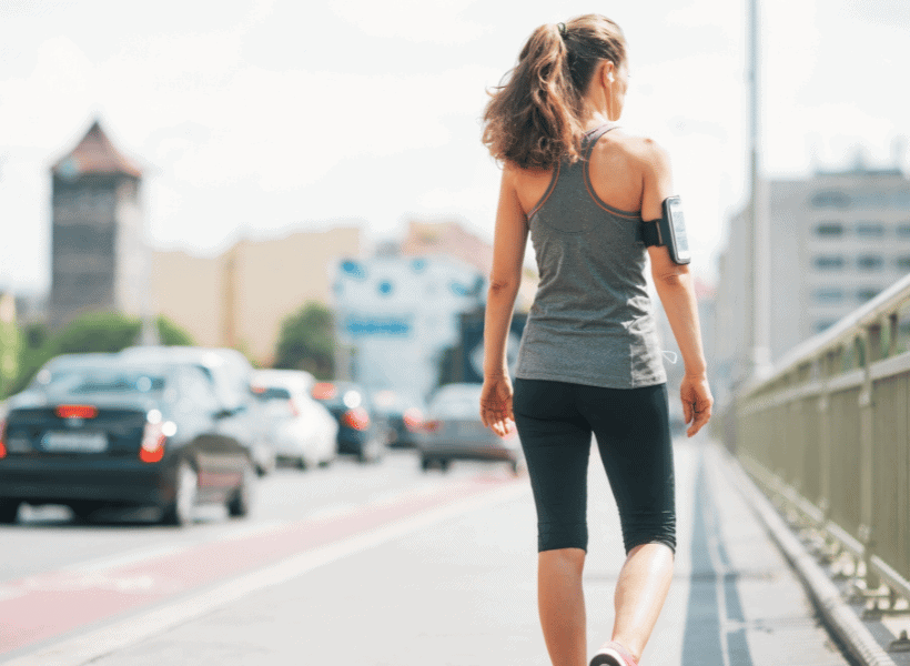 woman standing beside street with workout clothes on taking a break from running