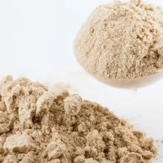 large scoop of protein powder and a pile of powder on the table beside it
