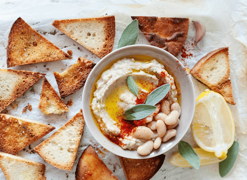 toasted pita bread with white bean dip in bowl with garnishment