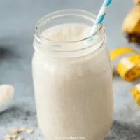 jar of protein shake with a straw with a measuring tape and weights laying beside it