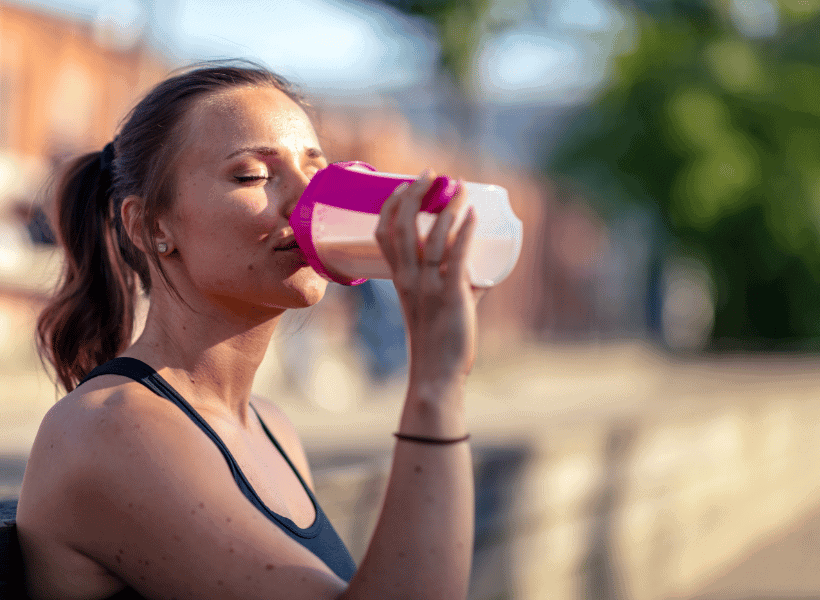 woman in fitness clothing drinking protein shake