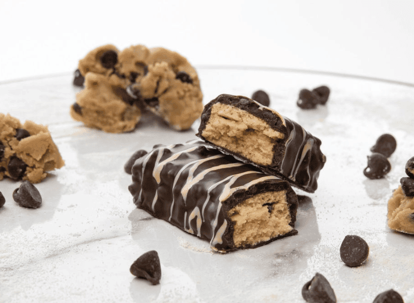 cookie dough protein bar broken in half on white table