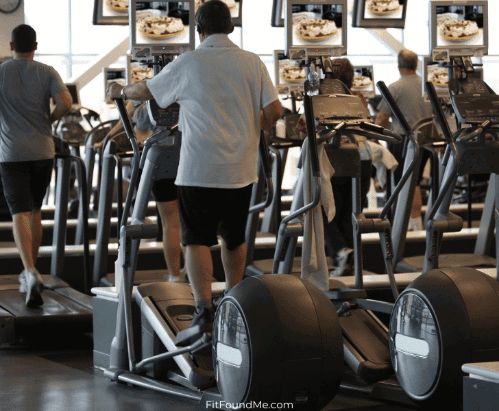 gym full of stairmaster and treadmill machines with men and women working out