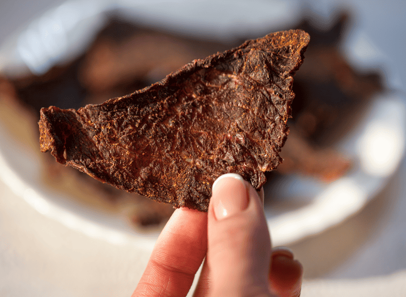 woman holding a piece of beef jerky