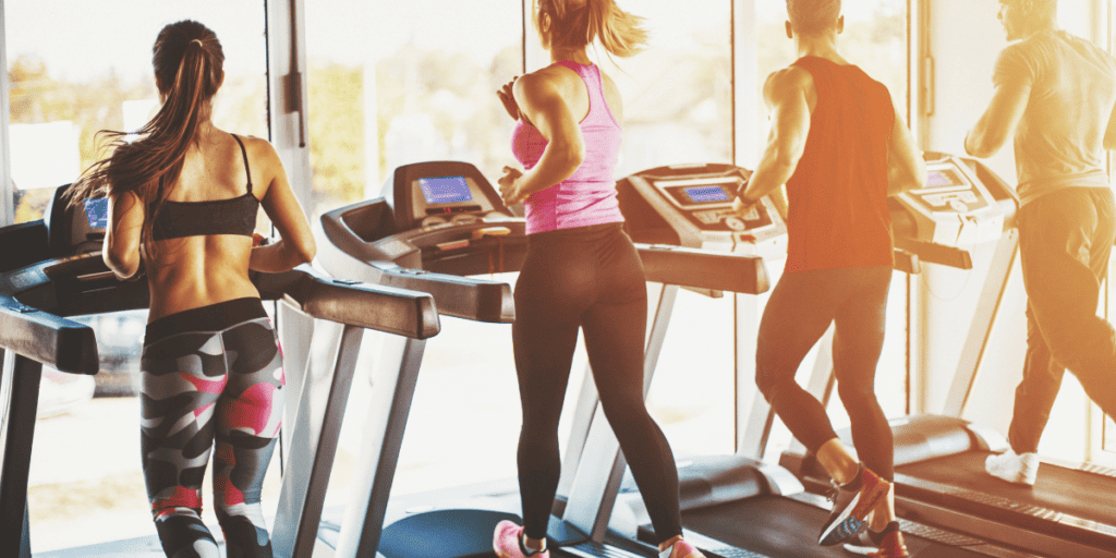 two women and two men on treadmills working out in gym