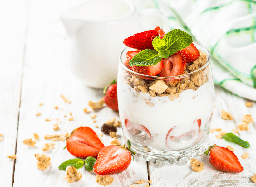 glass bowl of yogurt with granola and strawberries