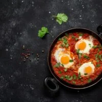 Shakshuka,Eggs,In,A,Pan,With,Toast,On,A,Black