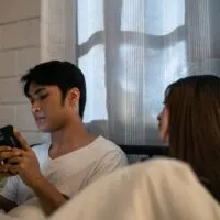 Asian,Man,Secretly,Chatting,To,Mistress,While,Sit,On,Bed