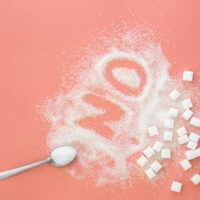 Word No made of sugar and spoon on pink background, flat lay.