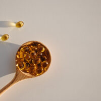 Capsules,With,Vitamin,D,In,Wooden,Spoon,On,The,White