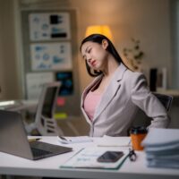 This Everyday Sitting Habit May Increase Your Risk of Blood Clots Female,Professional,Experiencing,Lower,Back,Pain,From,Prolonged,Computer,Work